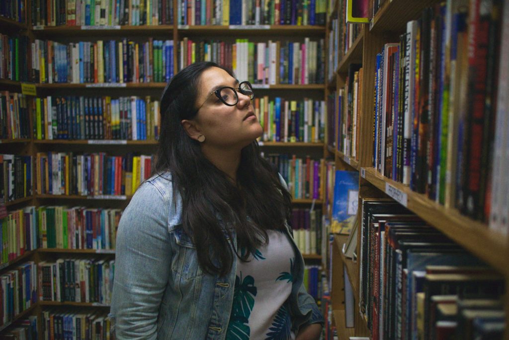 Photo of a person browsing books, surrounded by shelves of books